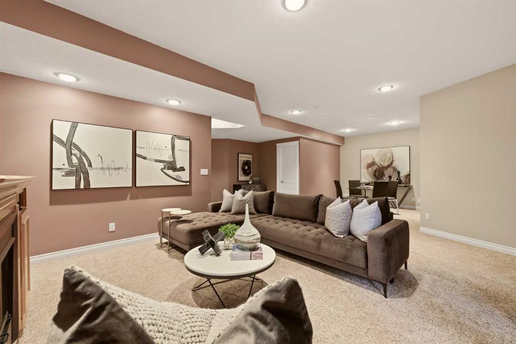 Basement living room with a brown sectional, round coffee table, beige carpet, and abstract wall art.