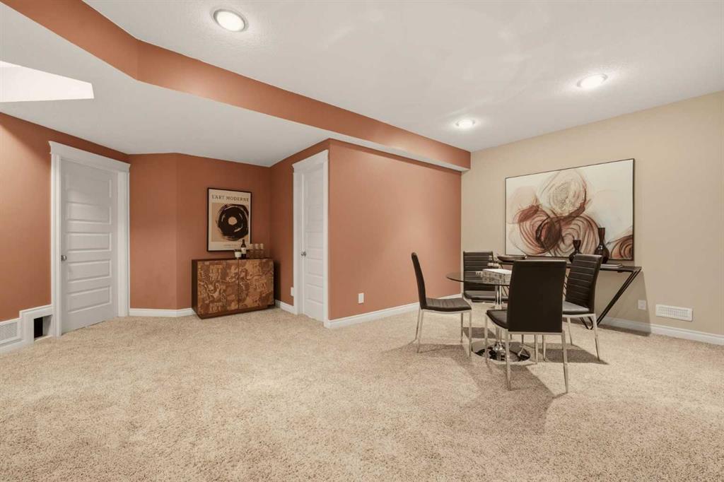 Carpeted dining area with a black table and chairs, terracotta walls, and two white paneled doors.