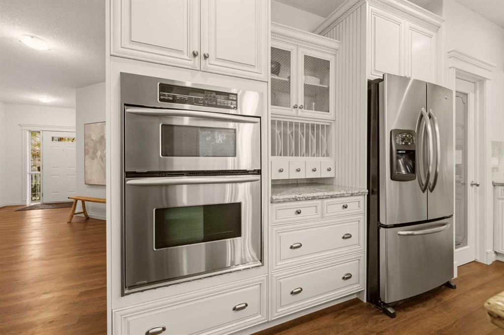 White kitchen with built-in double oven, French-door refrigerator, and granite countertop.