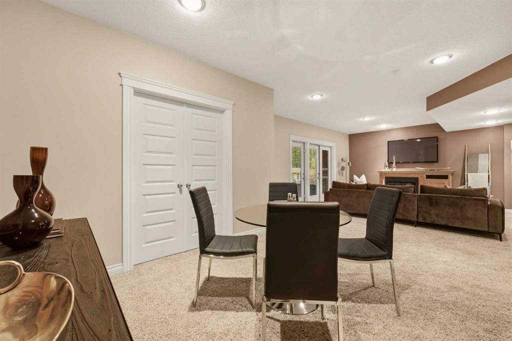 Furnished basement recreation room with brown sofas, a fireplace, and a dining table with black chairs.