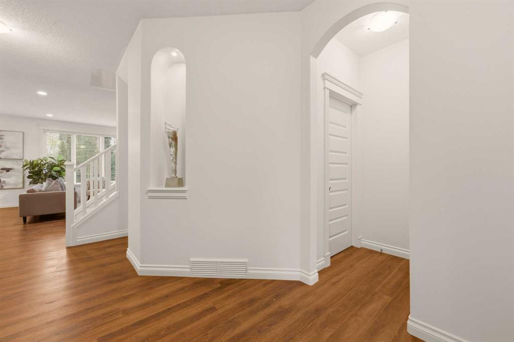 Foyer with warm hardwood floors, an arched doorway, and a recessed display niche.