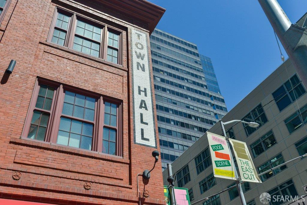 Brick Town Hall facade beside modern glass office buildings in downtown San Francisco.