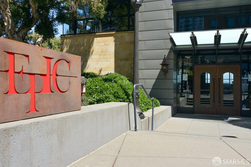 Residential building entrance with a red-lettered stone sign and glass canopy.