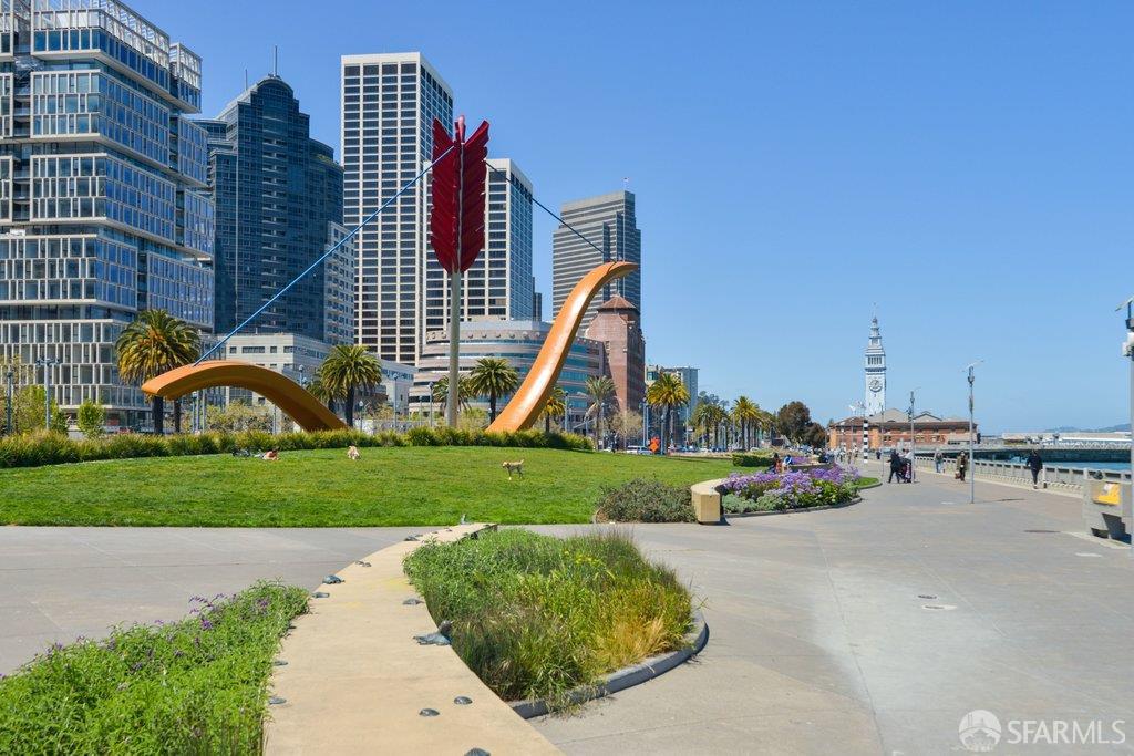 San Francisco waterfront park with Cupid’s Span sculpture, downtown towers, and the Ferry Building clock tower.