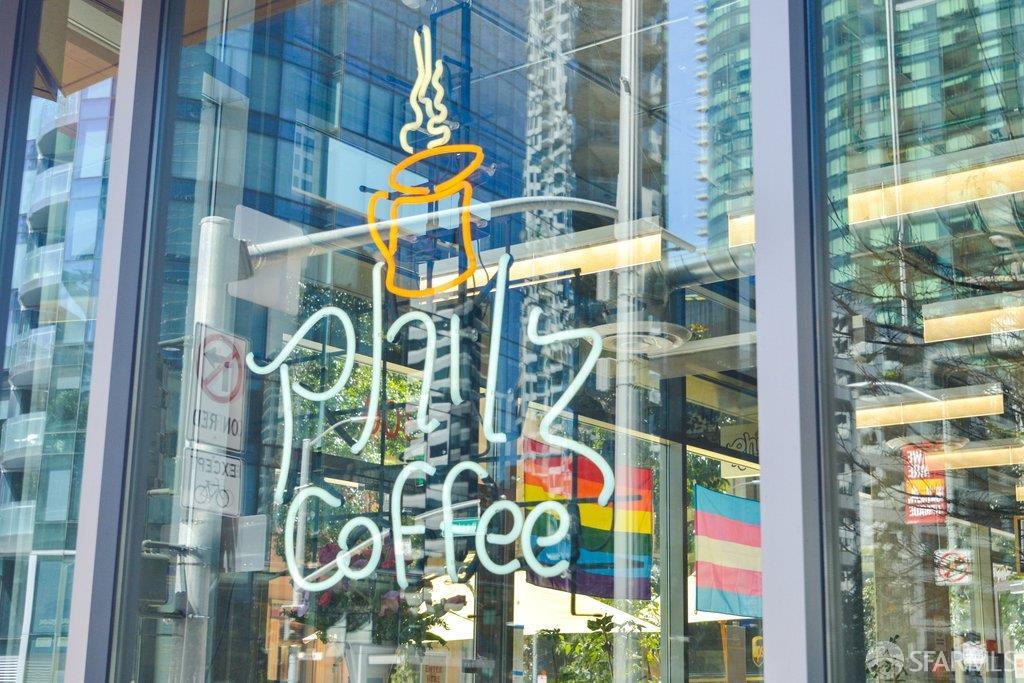 Philz Coffee storefront with a neon coffee cup sign and high-rise reflections.