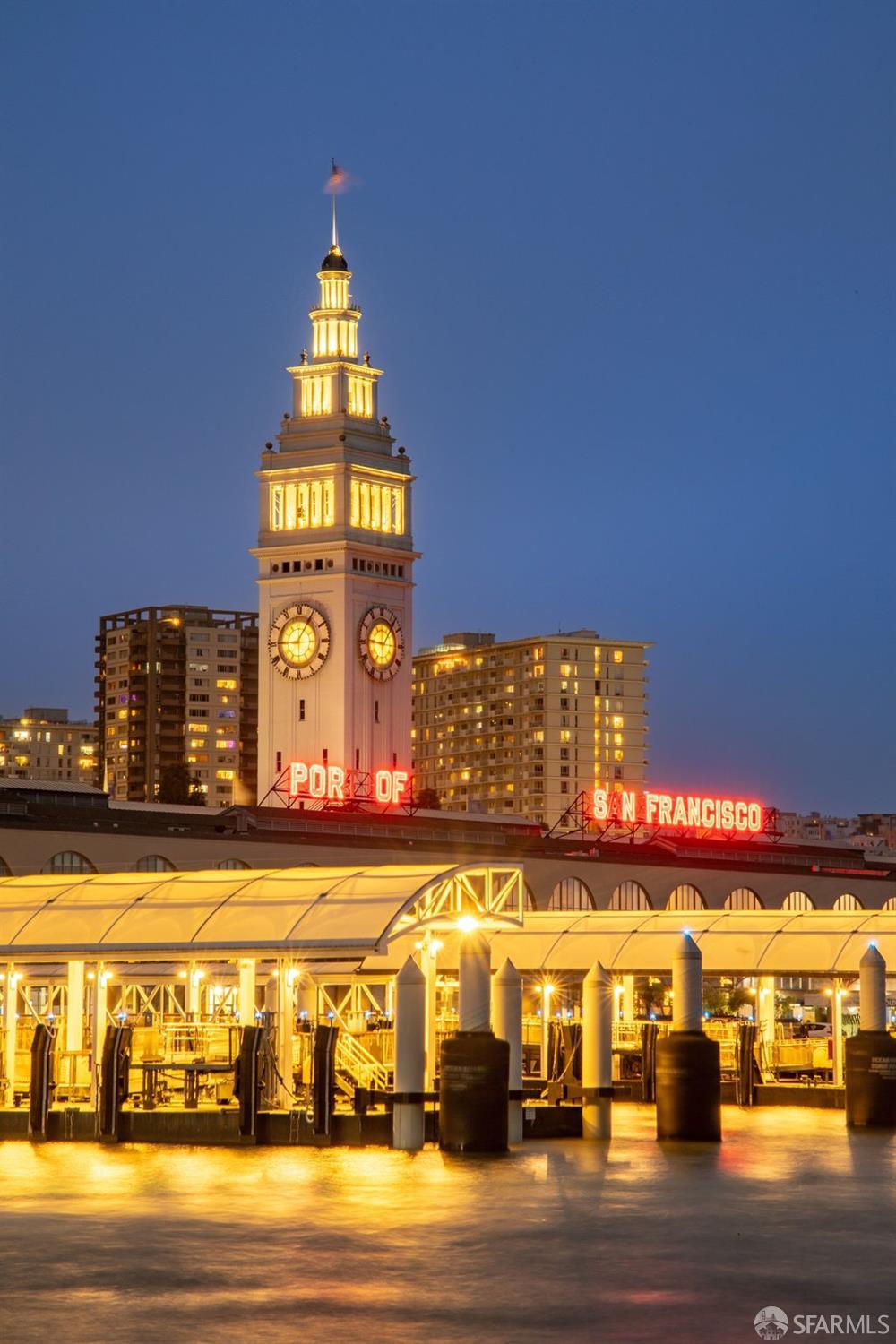 San Francisco Ferry Building clock tower and waterfront piers illuminated at dusk.