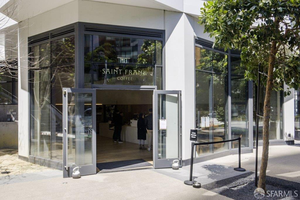 Saint Frank Coffee storefront with open glass doors and a leafy tree beside the sidewalk.