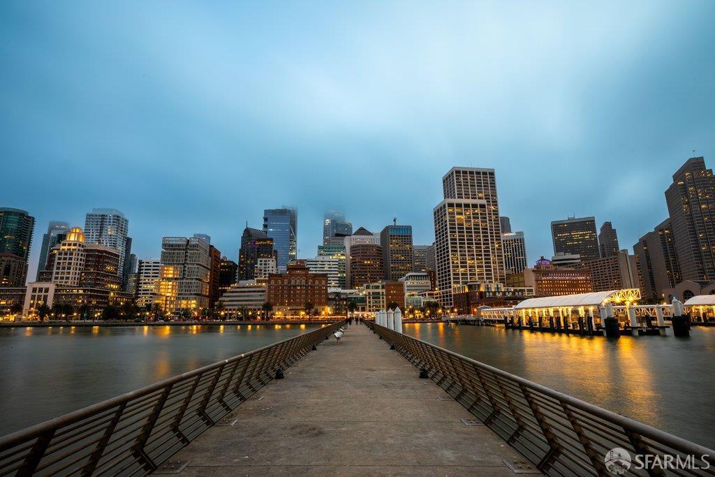 San Francisco waterfront skyline at dusk, viewed from a pier extending into the bay.