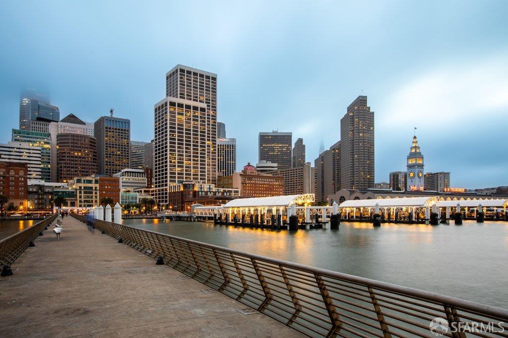 San Francisco skyline and waterfront at dusk, with the Ferry Building clock tower across the water.