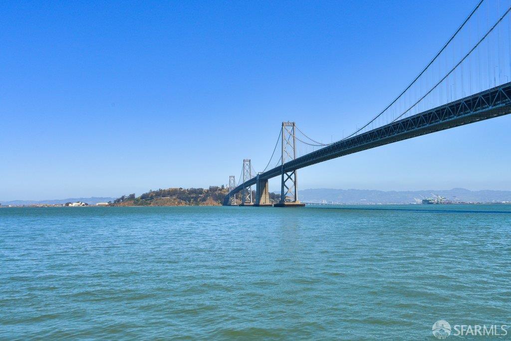 San Francisco Bay and the Bay Bridge, viewed across the water beneath a clear blue sky.