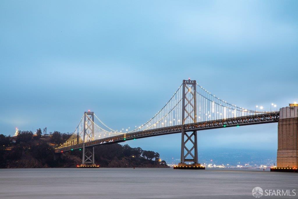 San Francisco–Oakland Bay Bridge illuminated at dusk across the water.