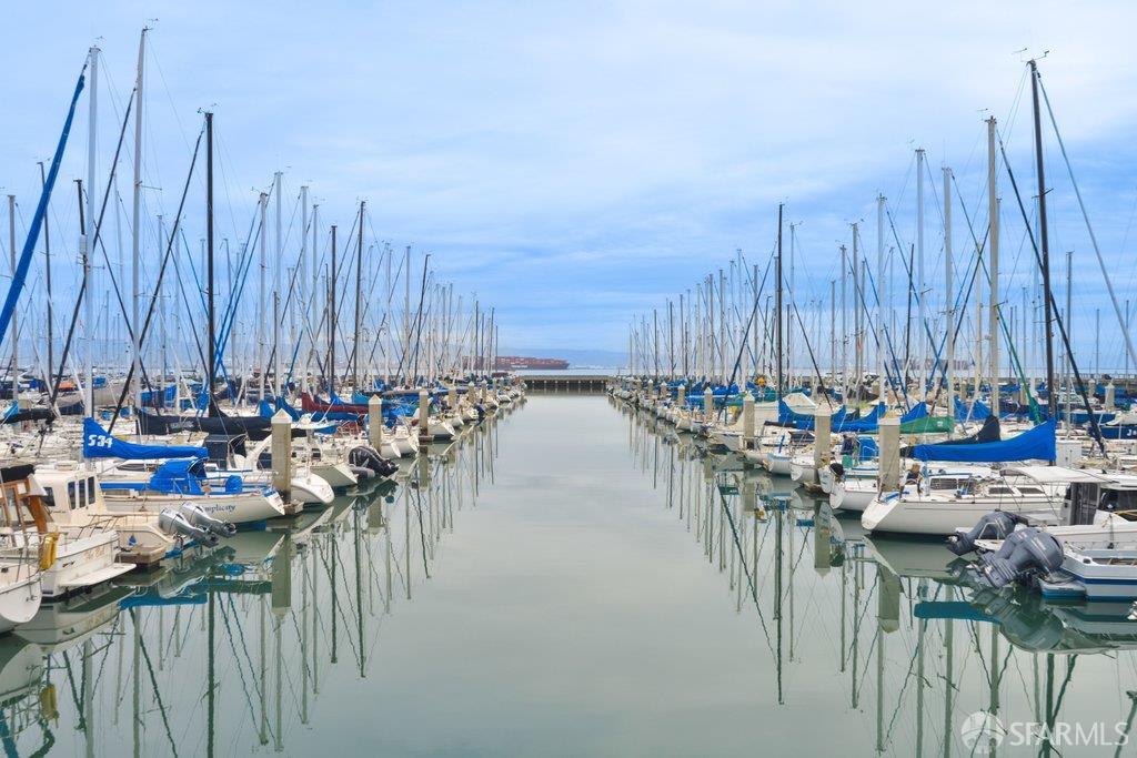 Sailboats and motorboats line a calm marina channel, their masts reflected in the water.