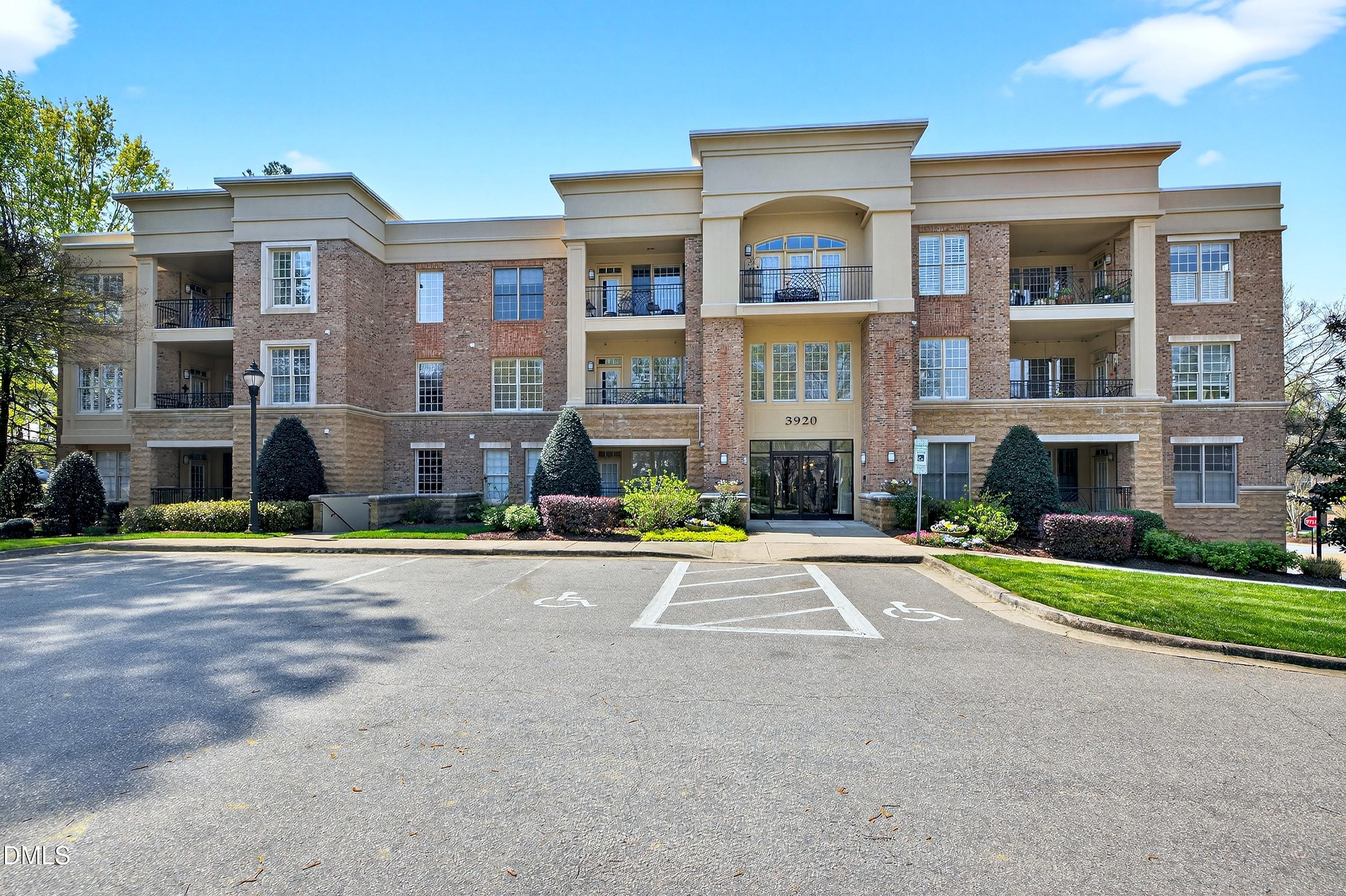 Brick-and-stone condominium building with balconies and an accessible parking area.