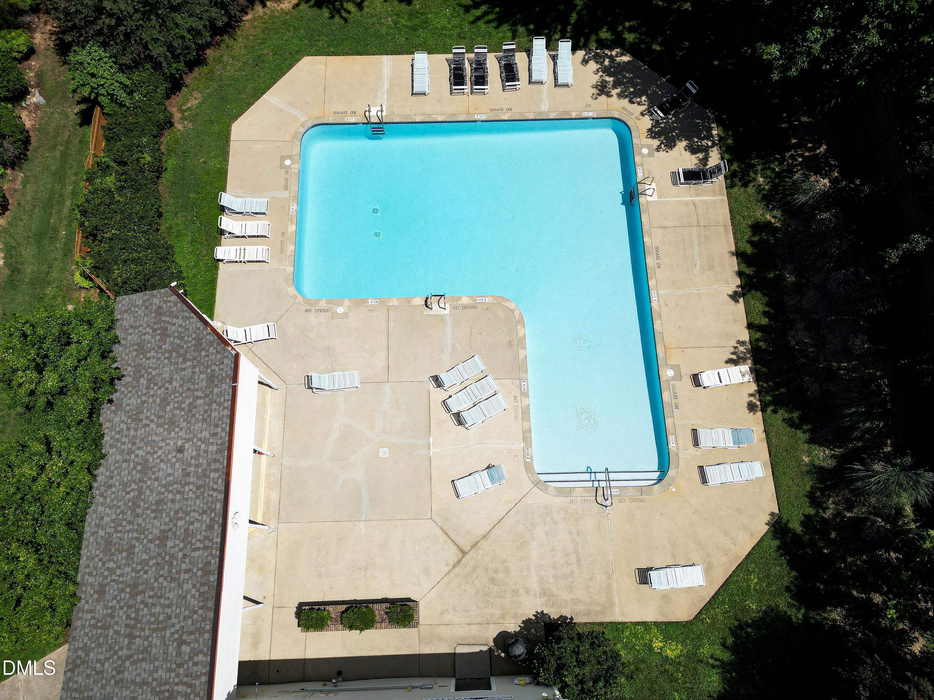 Aerial view of a large outdoor pool surrounded by lounge chairs and trees.