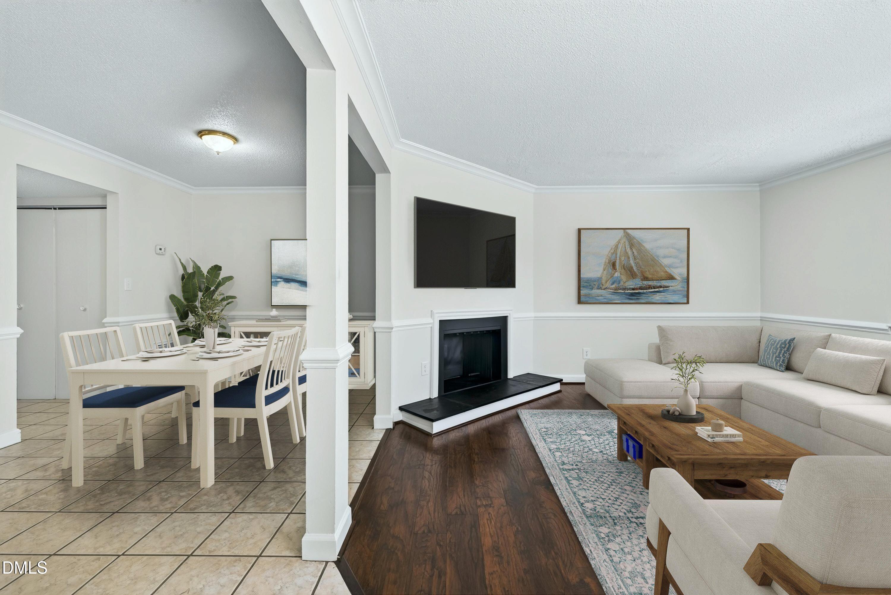 Open living and dining area with a fireplace, wall-mounted television, light sectional sofa, and tiled dining space.