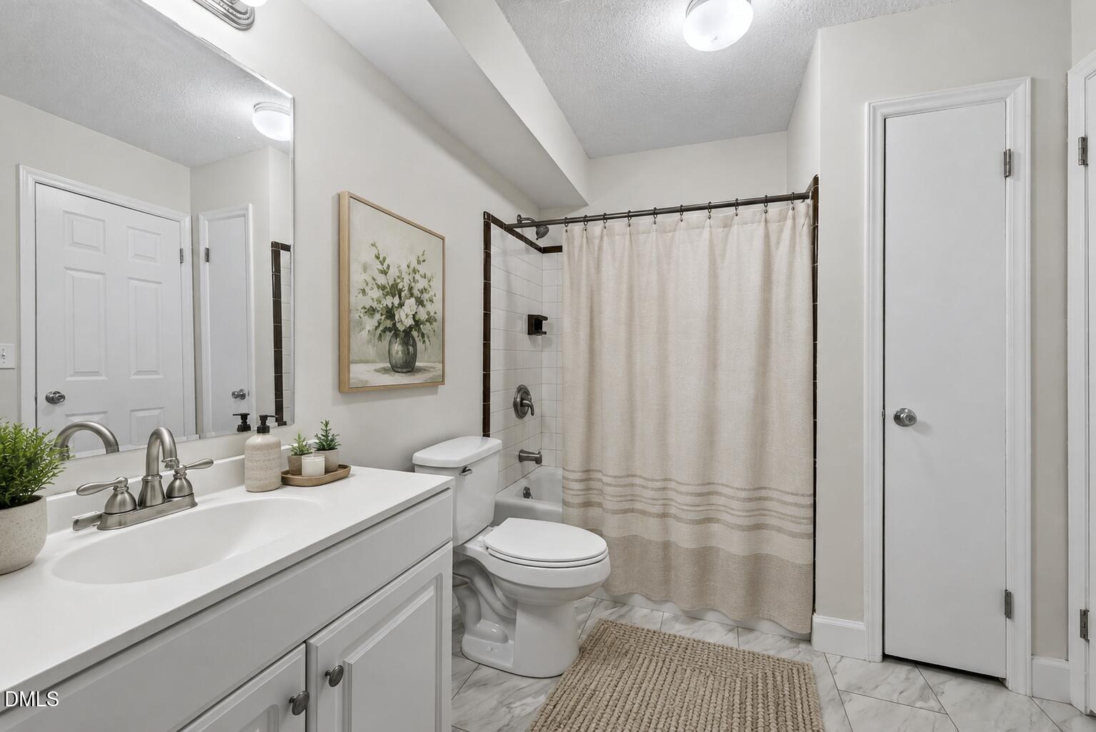 Bathroom with a white vanity, tiled tub-shower, and neutral curtain.