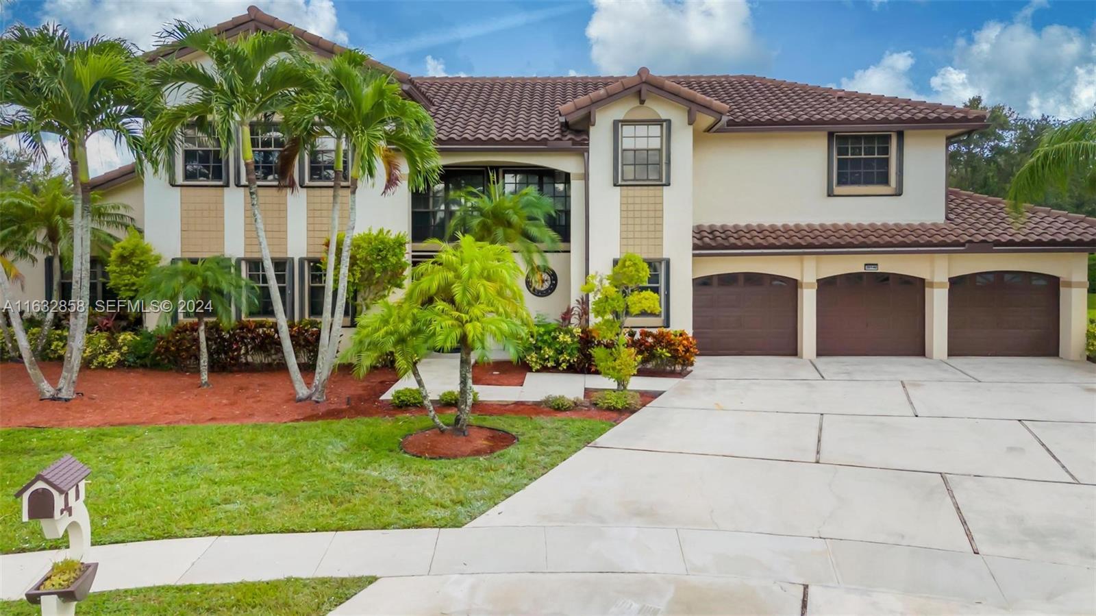 Two-story stucco home with a tile roof, three-car garage, palms, and a wide driveway.