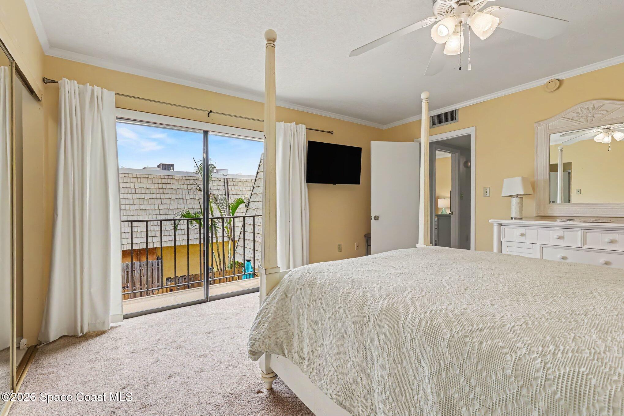 Bedroom with a white four-poster bed and sliding glass doors opening to a small balcony.