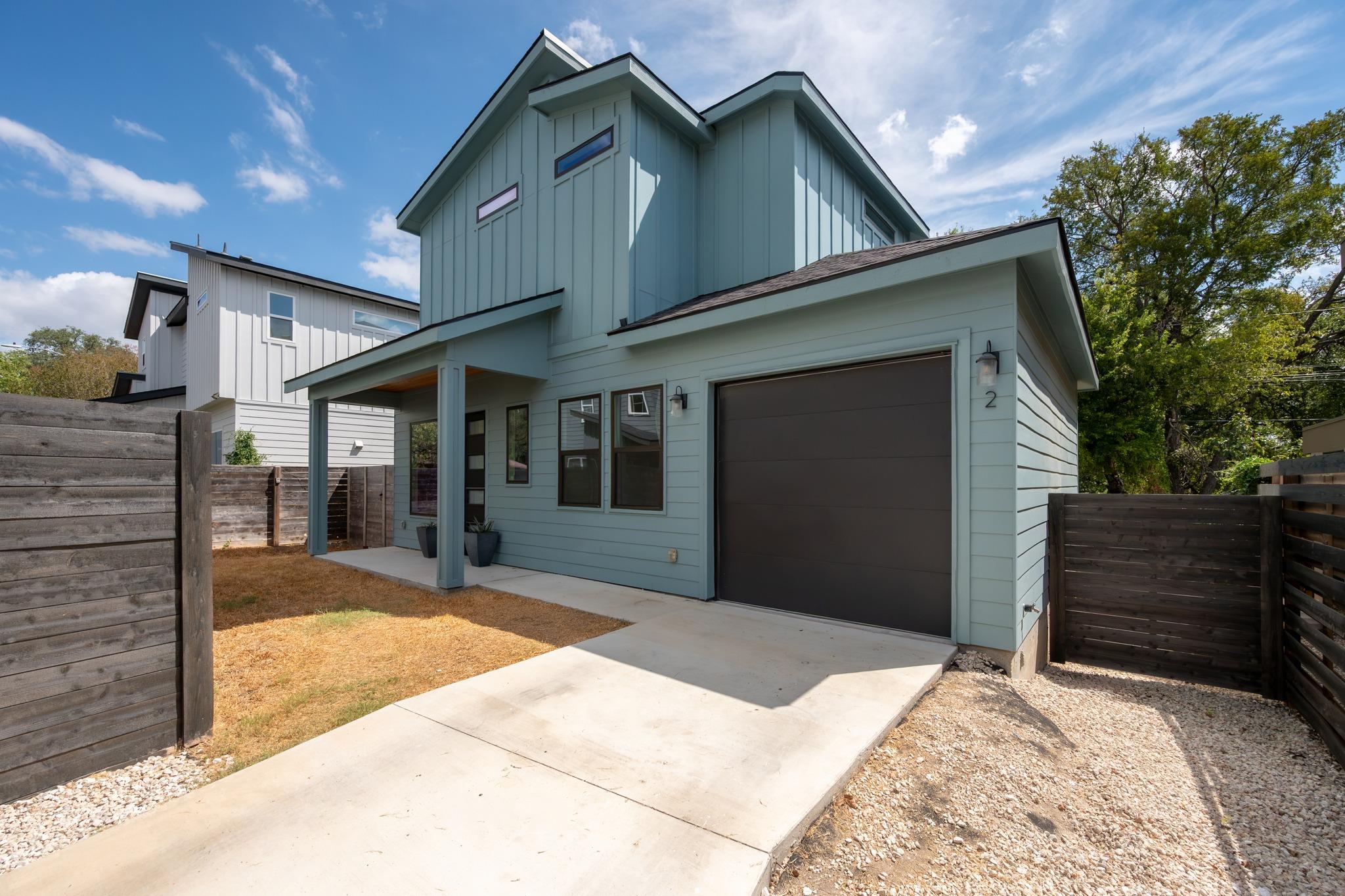 Blue-gray two-story home with an attached garage, covered entry, and fenced yard.