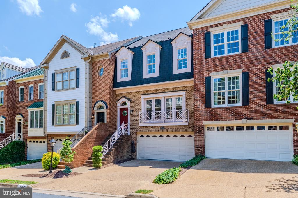 Attached townhouses with brick façades, dormer windows, front steps, and garages.