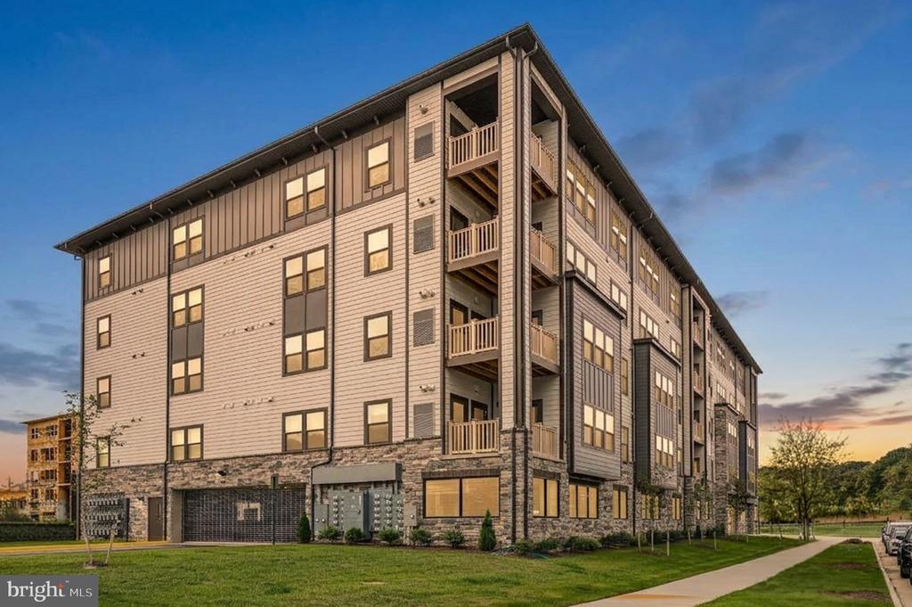 Multi-story apartment building with stacked balconies and stone veneer at dusk.