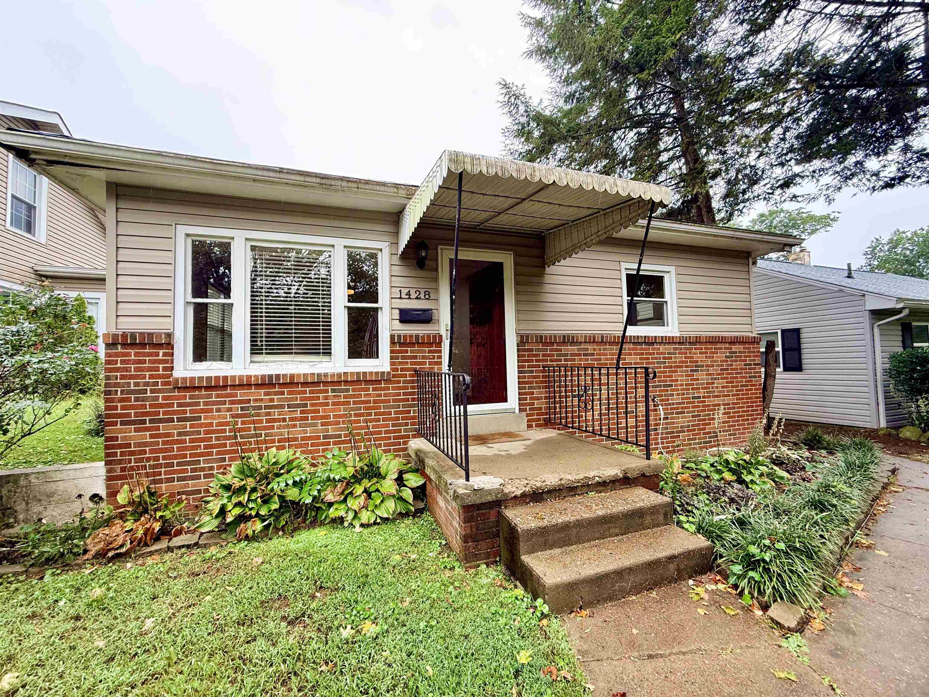 Huntington home with a red brick lower facade, beige siding, and a covered front entry.