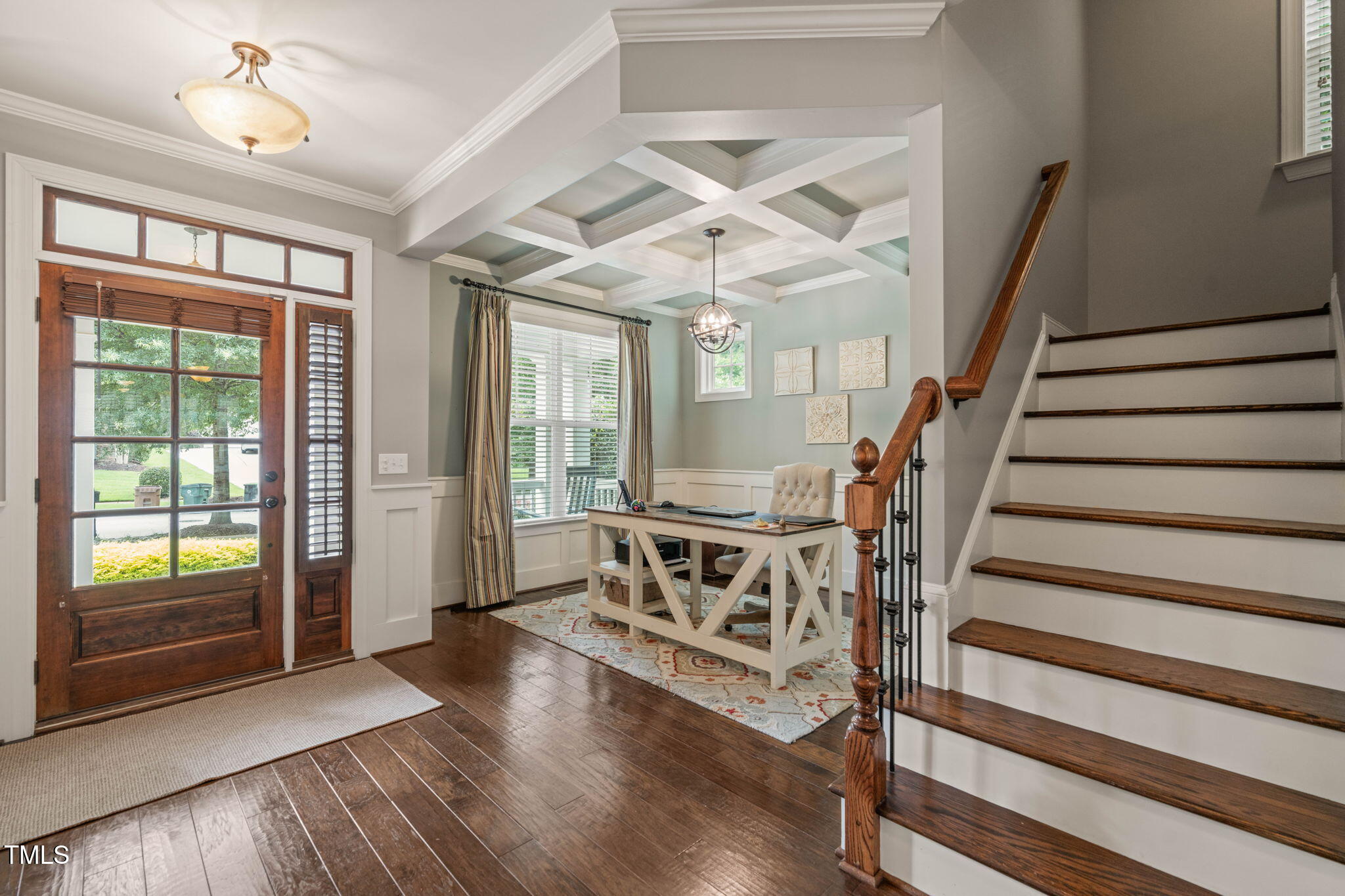 Foyer with a coffered ceiling, glass-paneled front door, desk, and hardwood staircase.