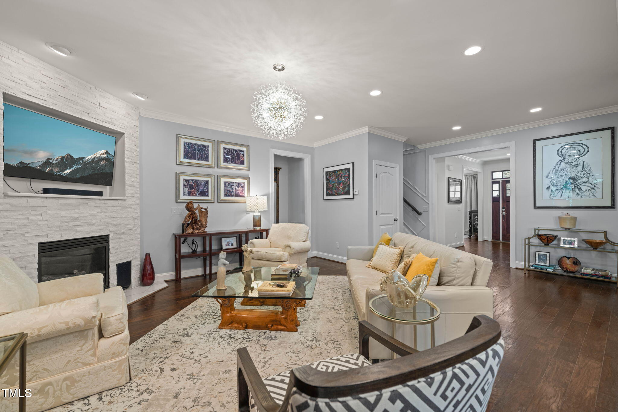 Furnished living room with a white stone fireplace, cream sofas, and dark wood floors.