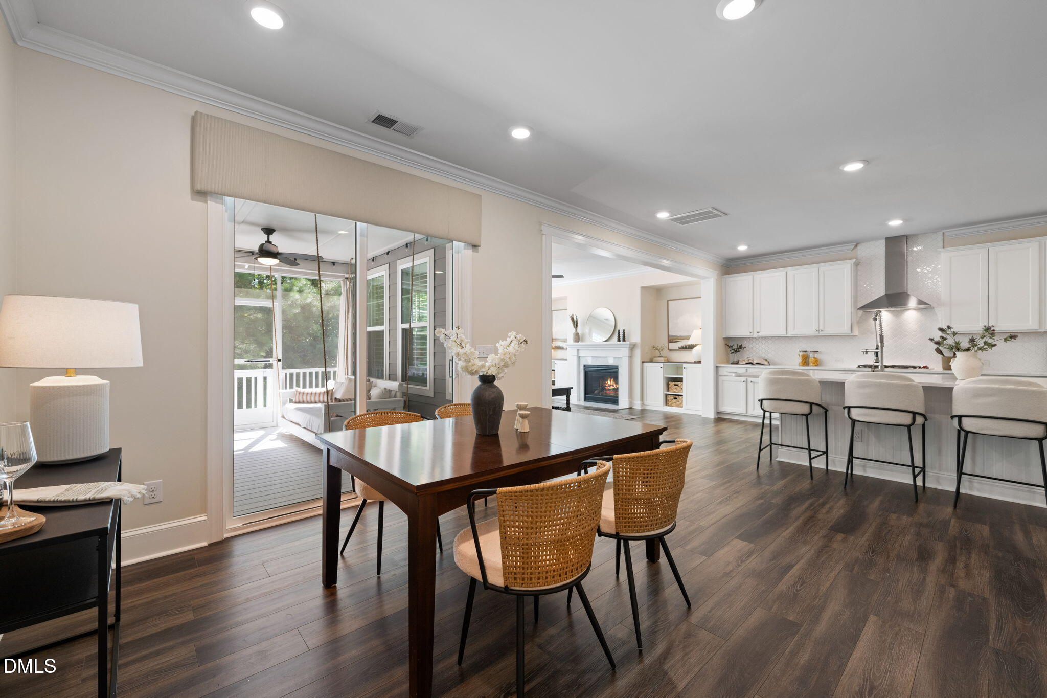Dining room and kitchen with a dark wood table, white cabinetry, and sliding doors to a screened porch.