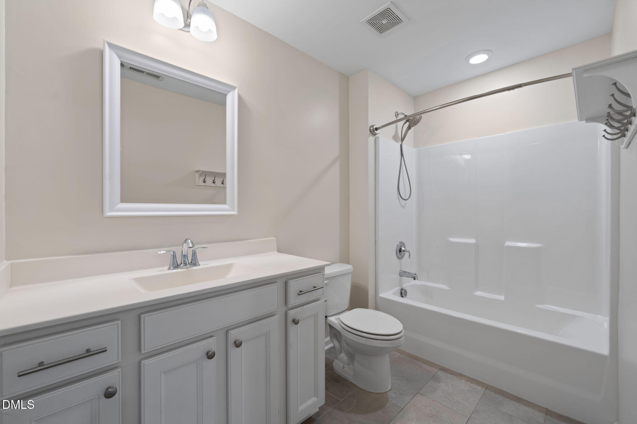Bathroom with a white paneled vanity, framed mirror, and tub-shower combination.