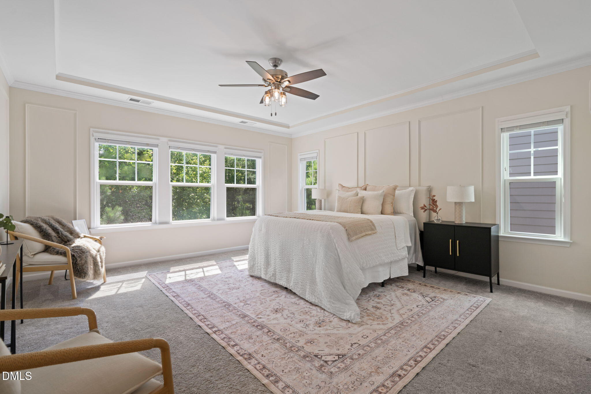 Bright bedroom with a white bed, large windows, a patterned rug, and a ceiling fan.