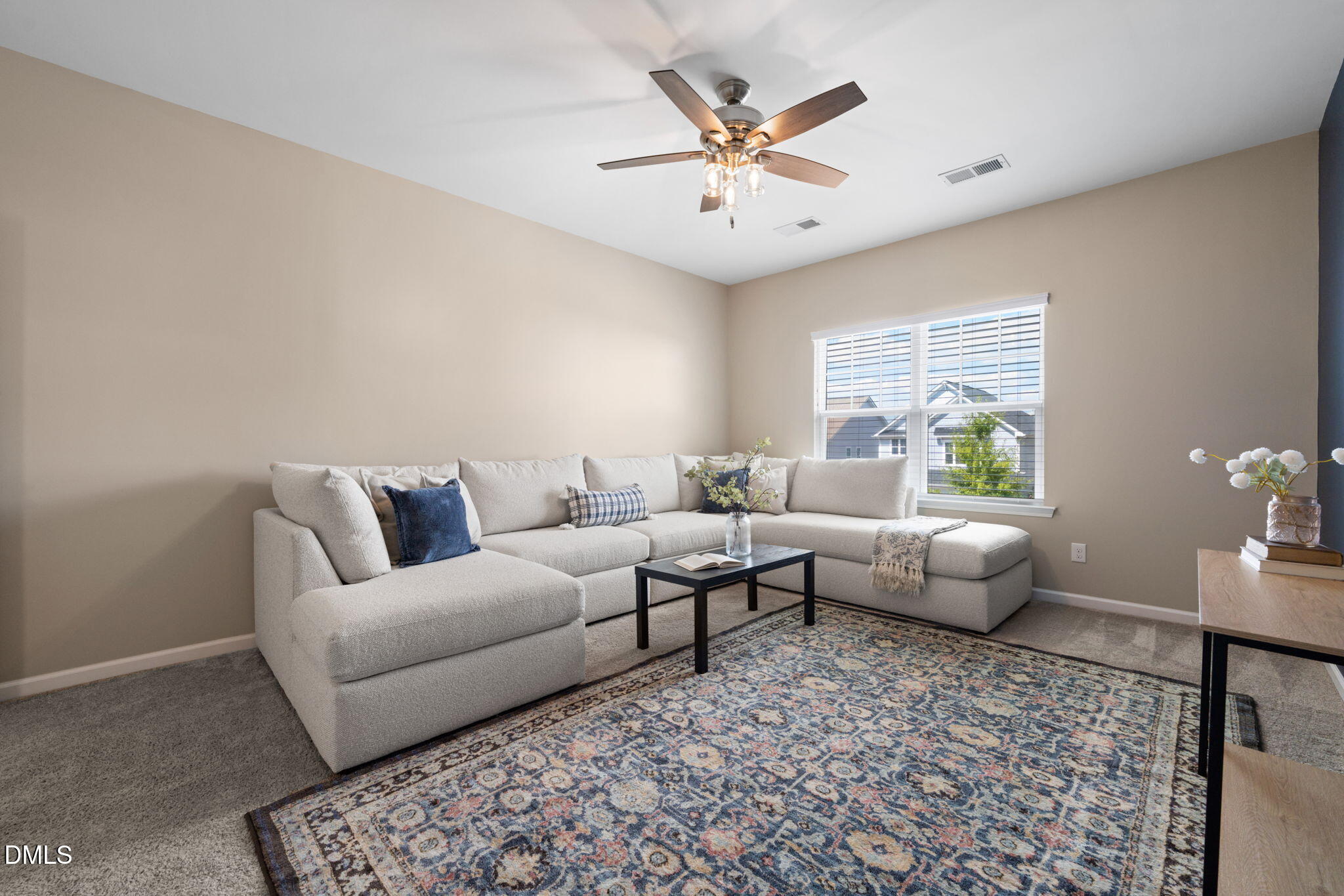 Furnished living room with a light sectional, patterned rug, and ceiling fan.