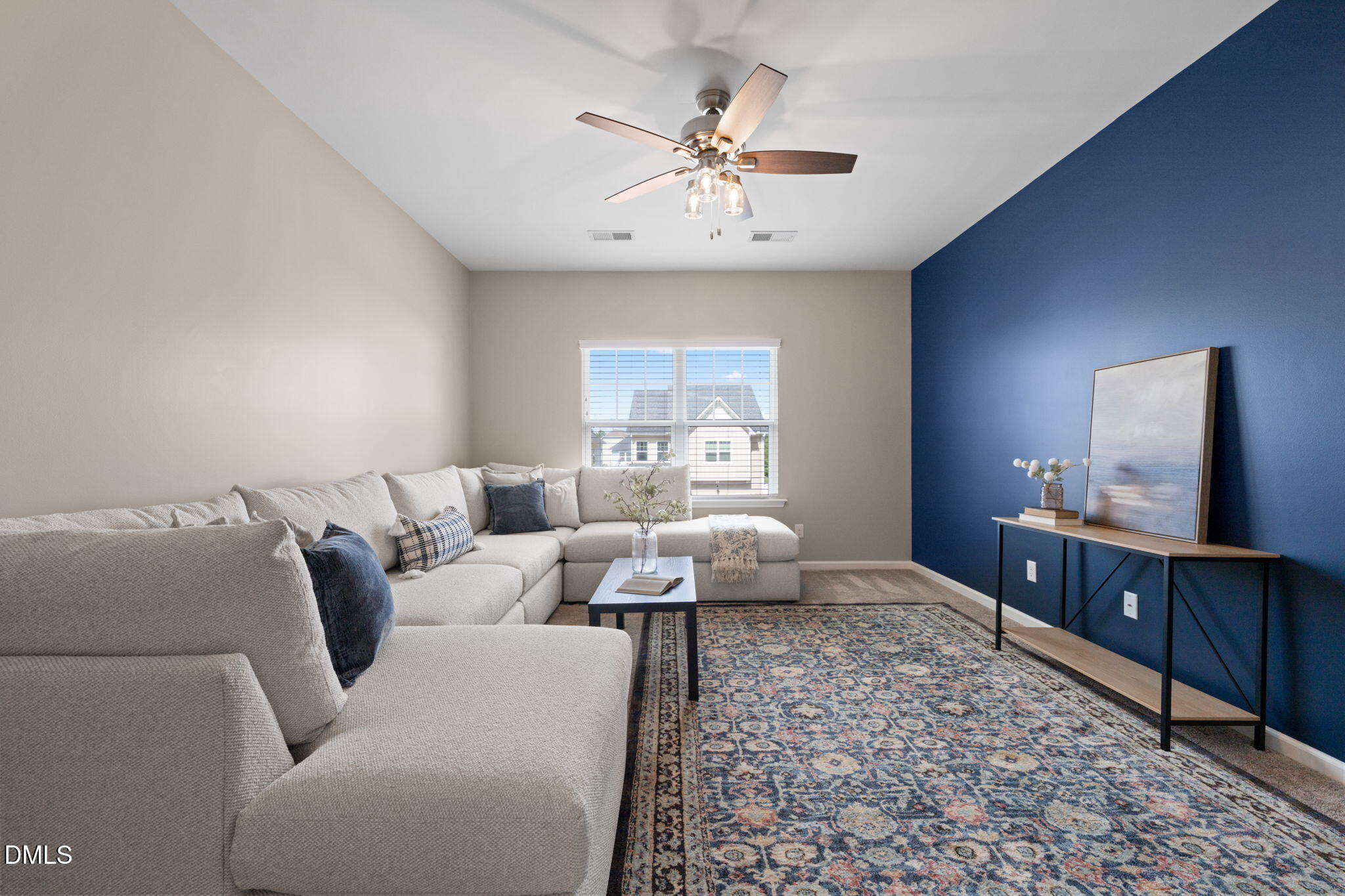 Living room with a large sectional, patterned rug, blue accent wall, and ceiling fan.