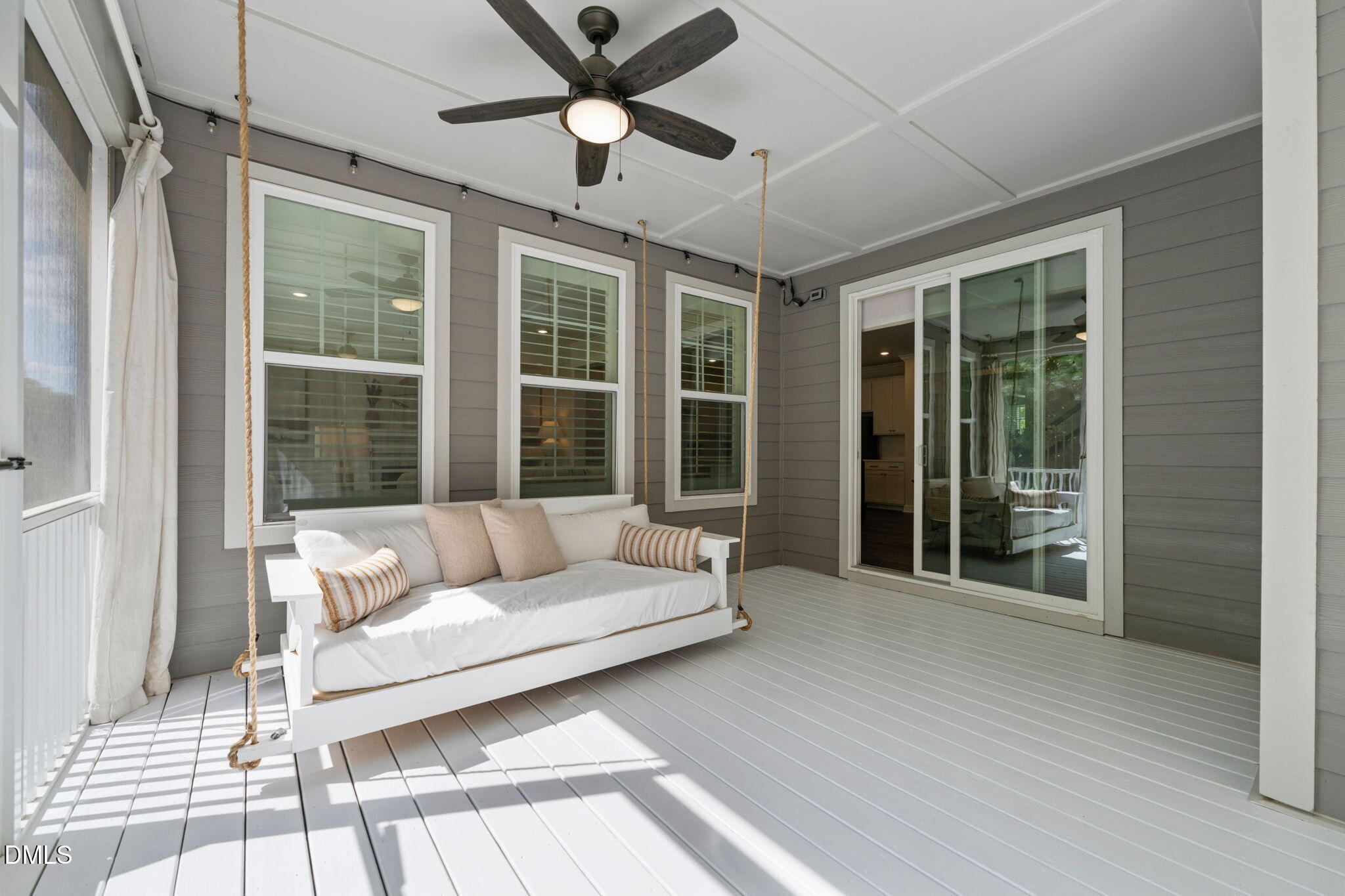Covered porch with a white rope-hung swing, gray siding, and sliding glass doors.
