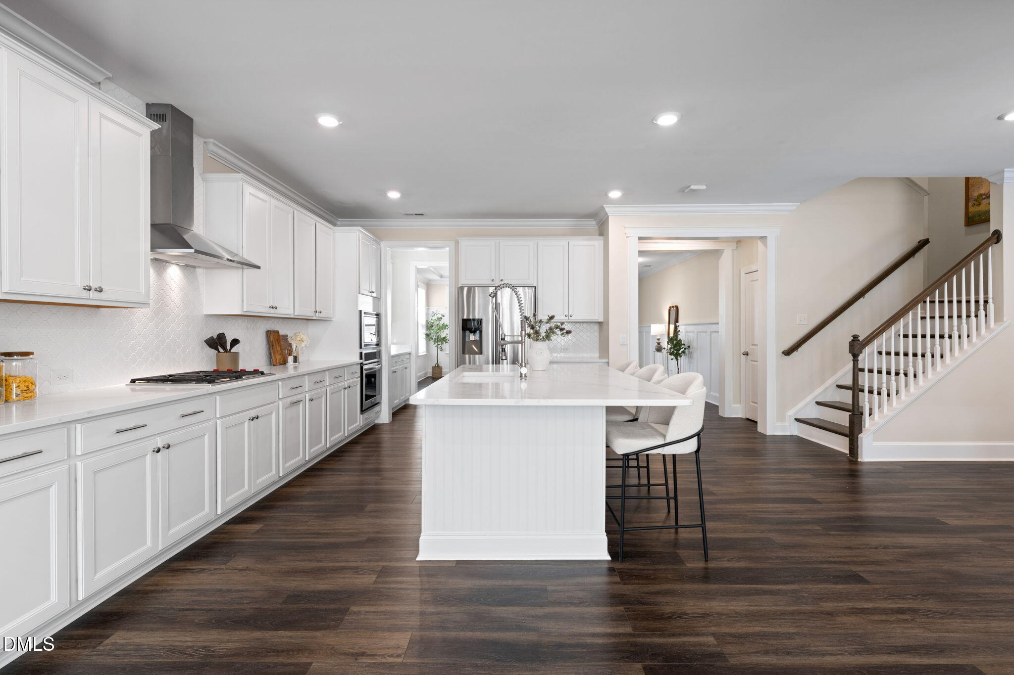 Bright kitchen with white cabinetry, a large island, stainless steel appliances, and dark wood floors.