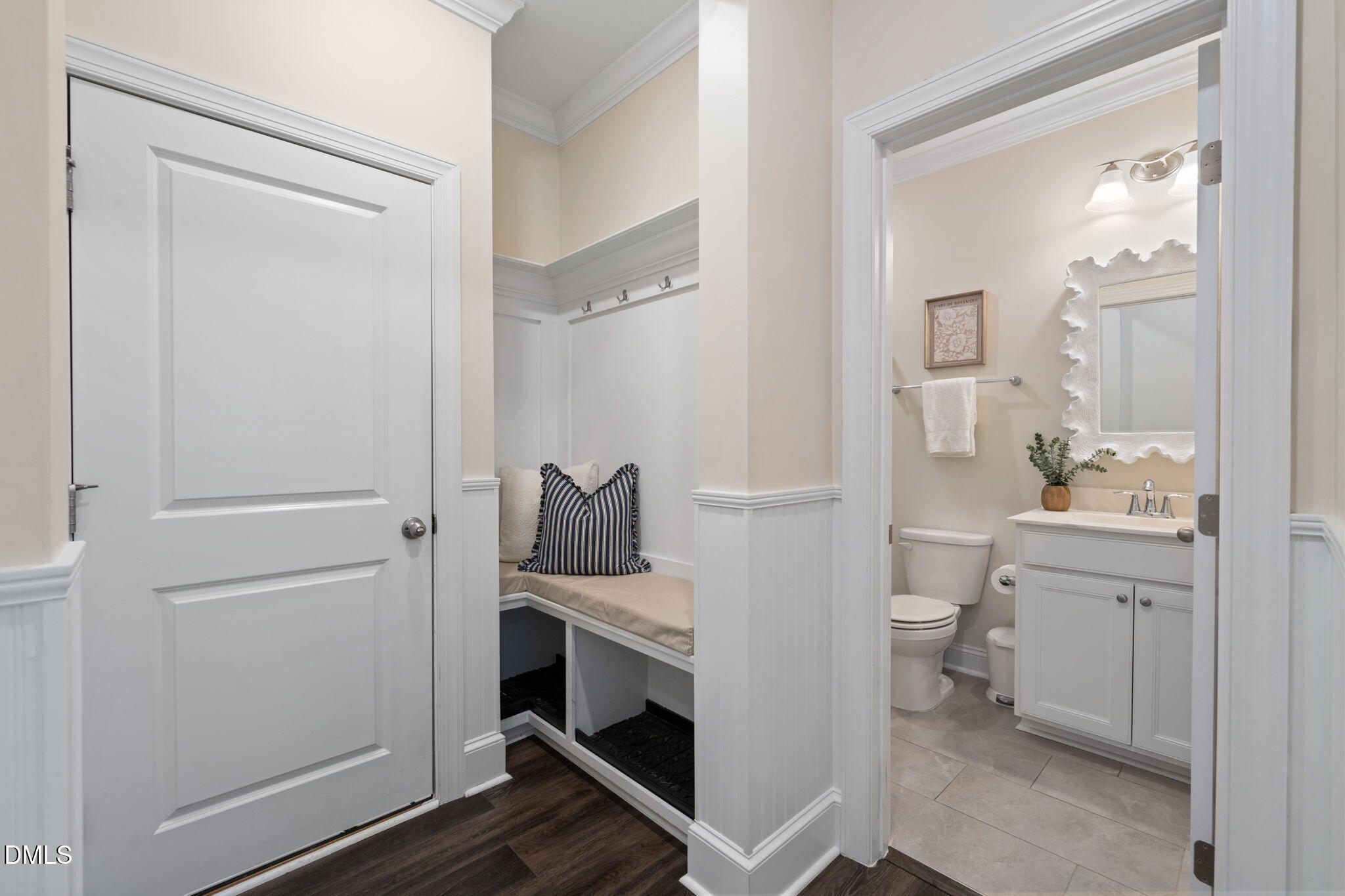 Entryway with a built-in cushioned bench beside an open powder room with a white vanity.