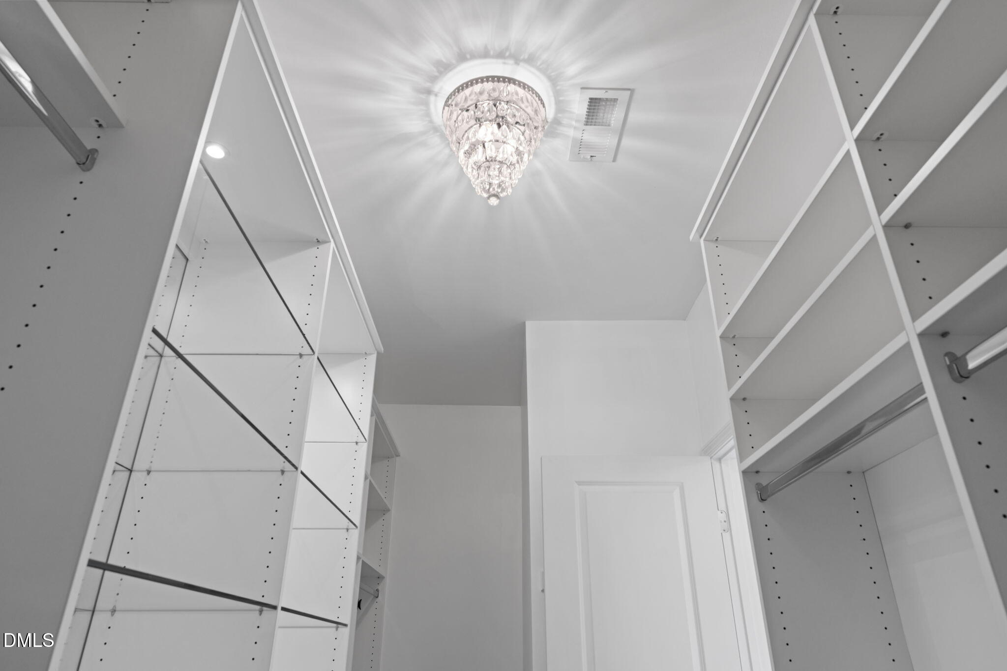 Walk-in closet with built-in shelving, hanging rods, and a crystal chandelier.