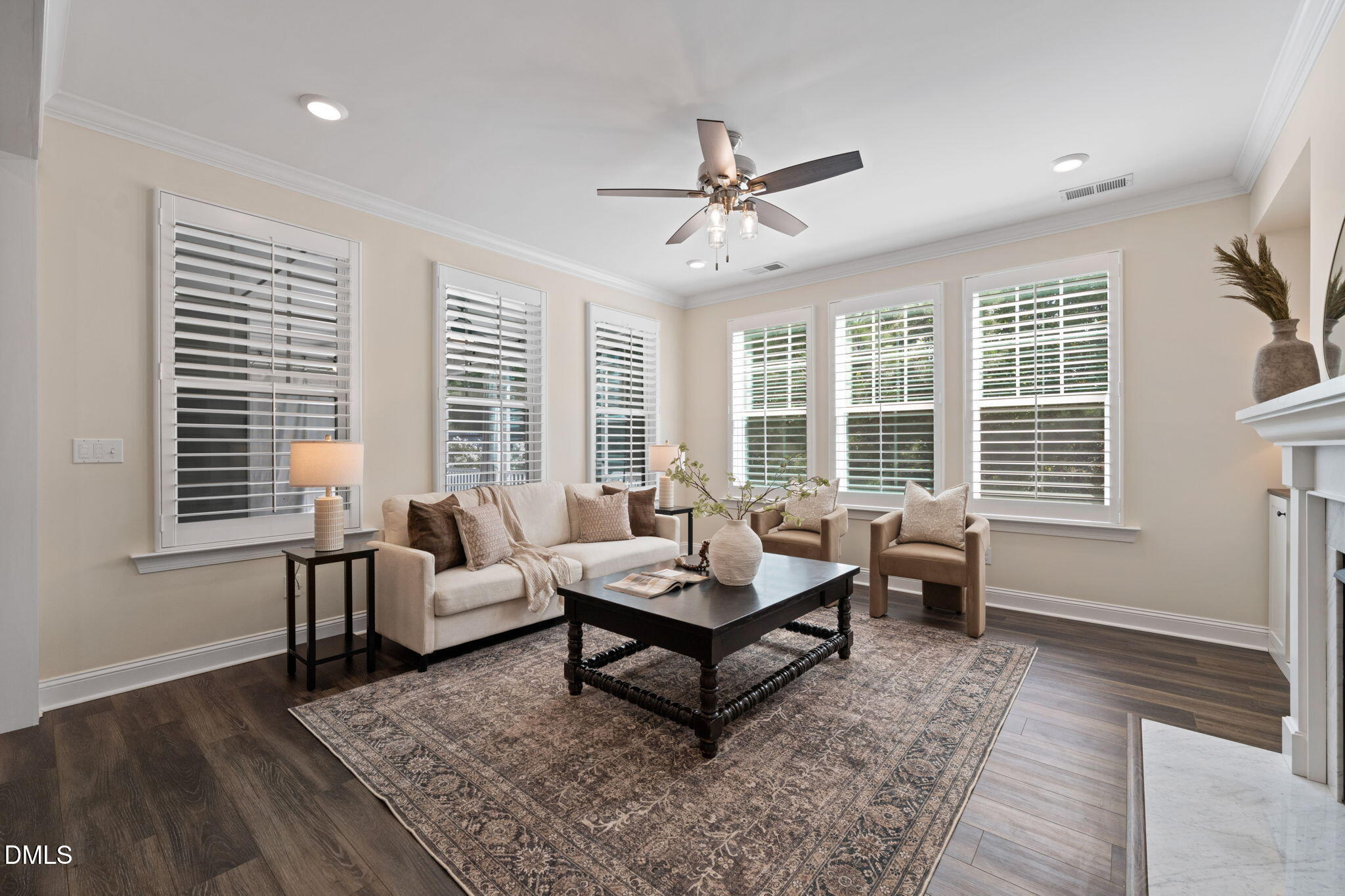 Furnished living room with plantation shutters, a patterned rug, and a ceiling fan.