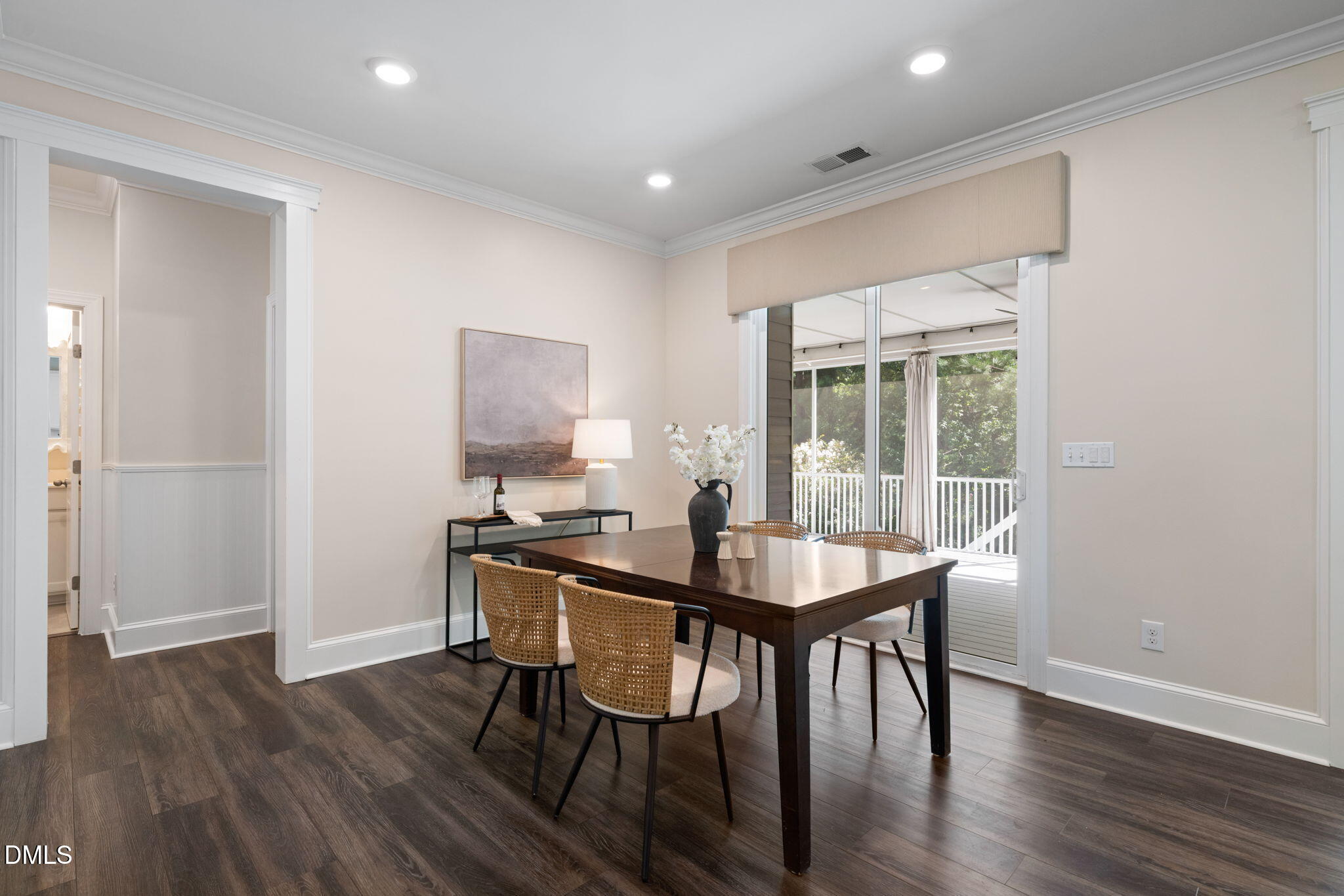 Dining room with a dark wood table and woven chairs beside sliding doors to a covered deck.