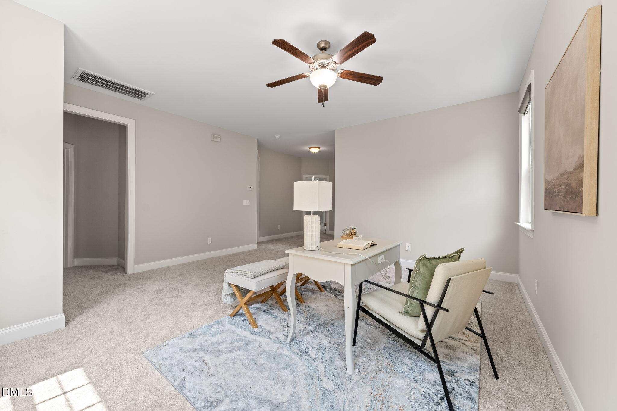 Staged home office with a white desk, upholstered chairs, patterned rug, and ceiling fan.