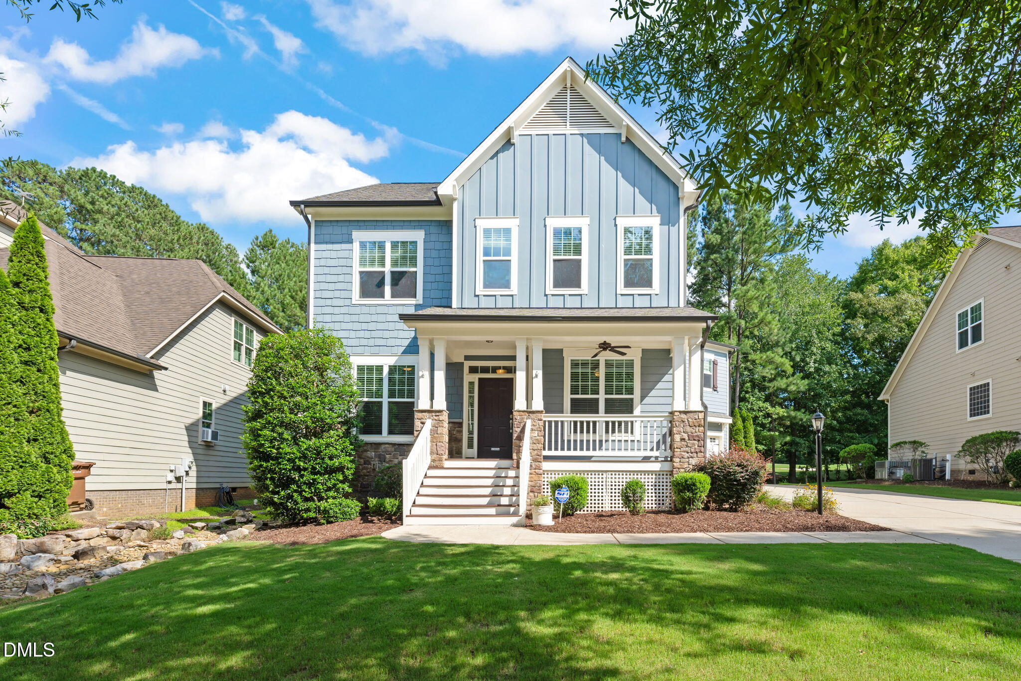 Blue two-story house with white trim, a covered porch, stone supports, and front steps.