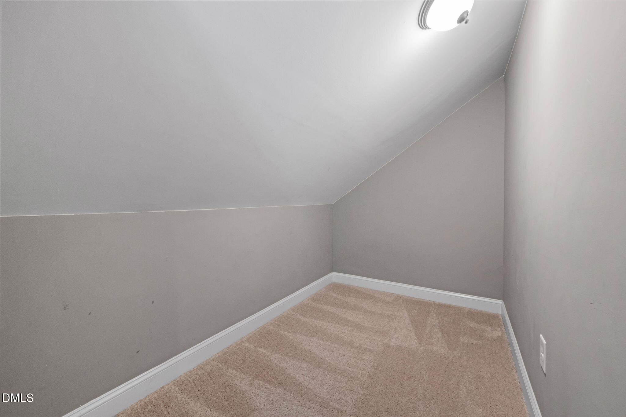 Empty carpeted room with gray walls and a sloped ceiling.