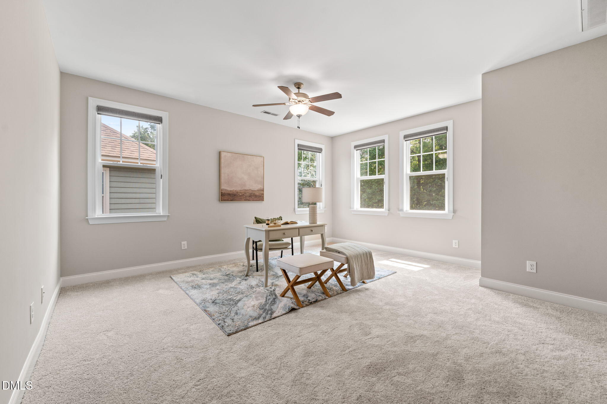Bright carpeted home office with a desk, patterned rug, and four windows.