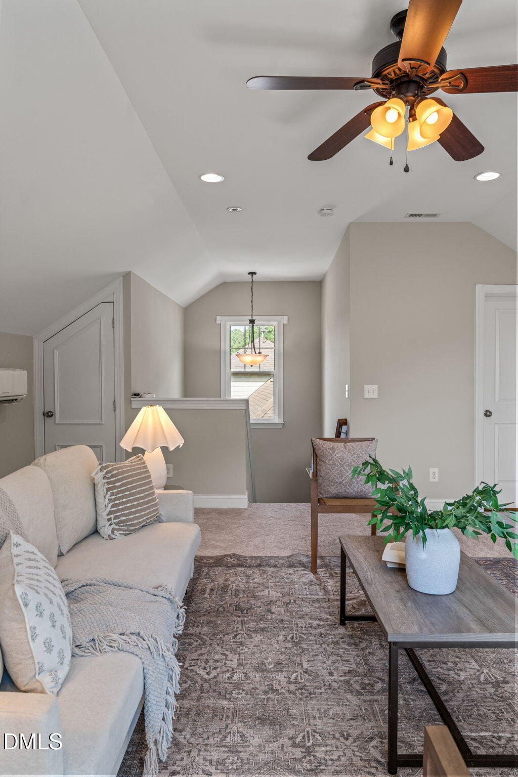 Furnished sitting area with a vaulted ceiling, dark wood ceiling fan, cream sofa, and patterned rug.