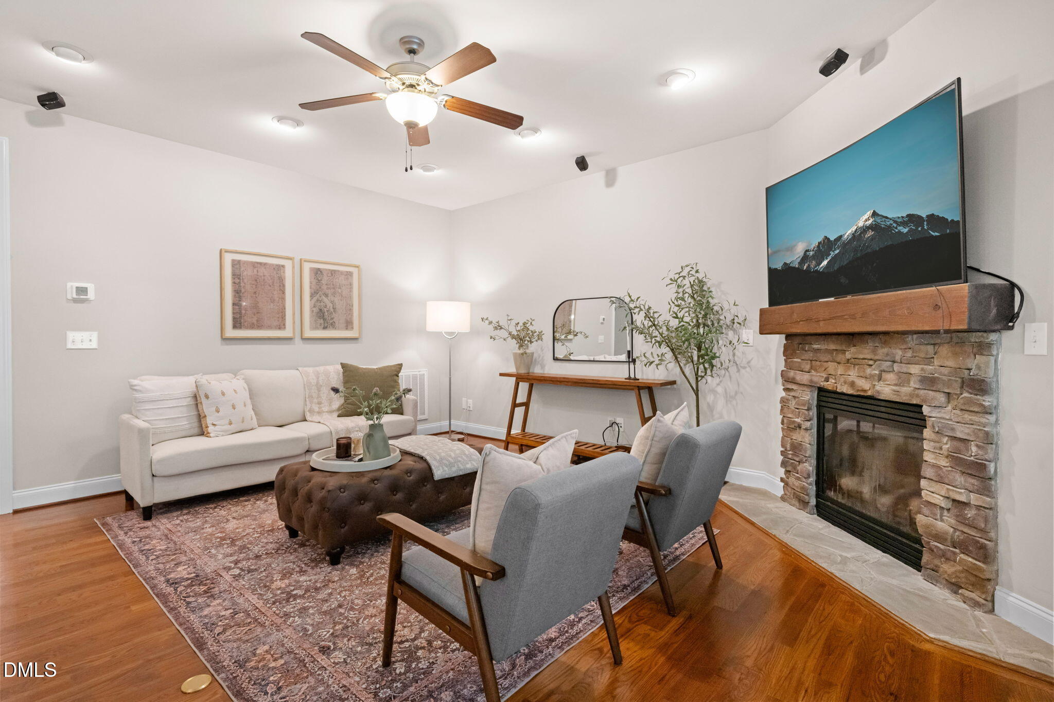 Furnished living room with a stone fireplace, television, and seating arranged on a patterned rug.