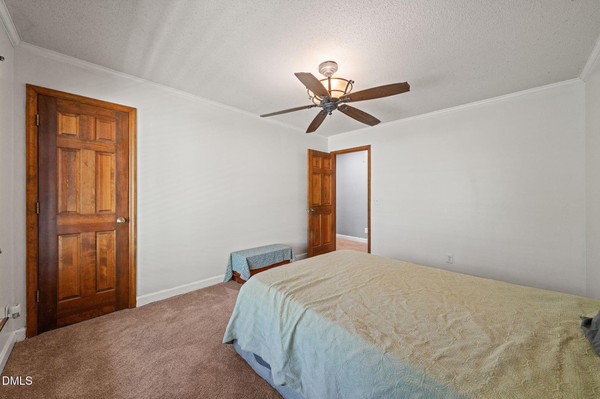 Bedroom with a pale blue quilt, beige carpet, dark wood doors, and a ceiling fan with a light.