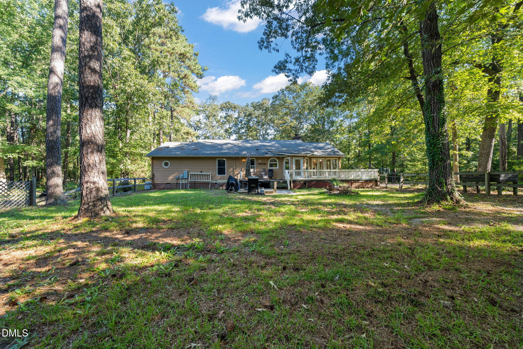 Single-story home with a raised deck in a spacious, wooded backyard.