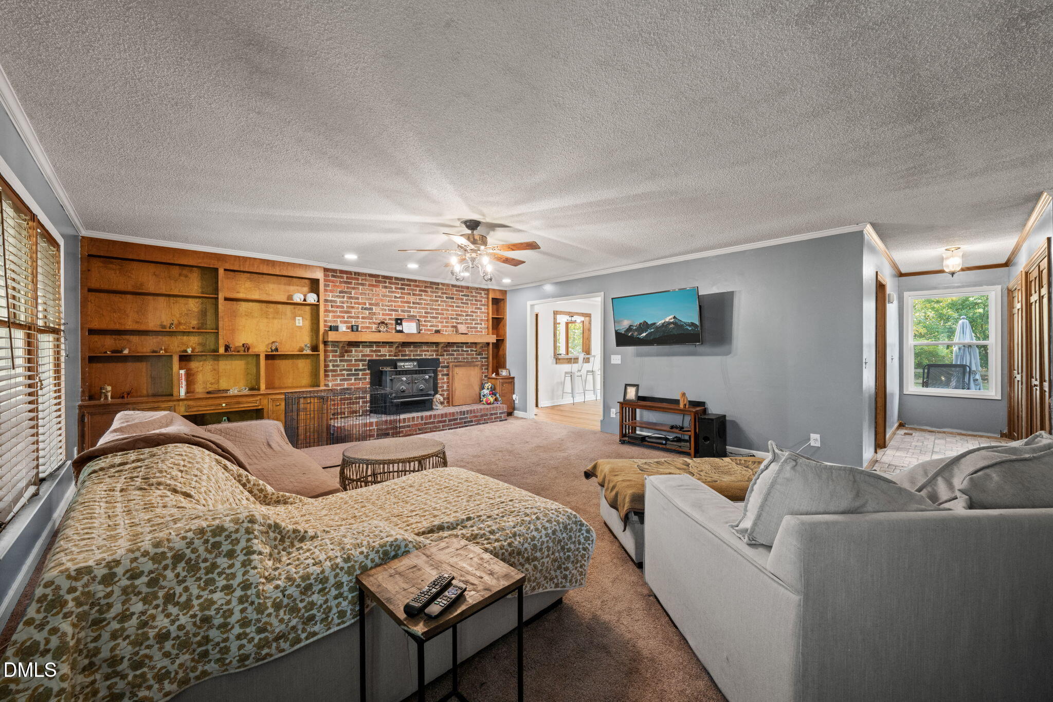 Furnished living room with brick fireplace, extensive wood built-ins, and seating around a television.