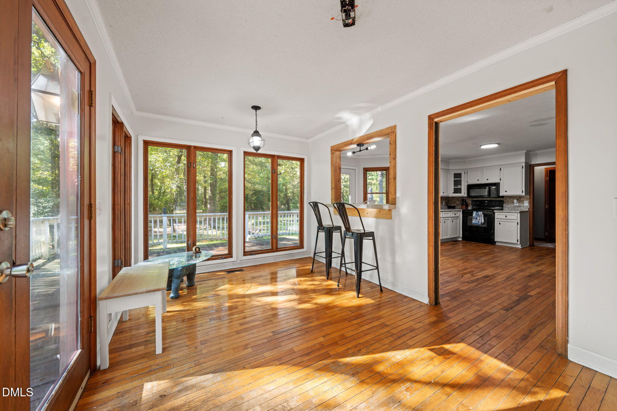 Dining area with polished hardwood floors, wood-trimmed windows, and a pass-through to the kitchen.