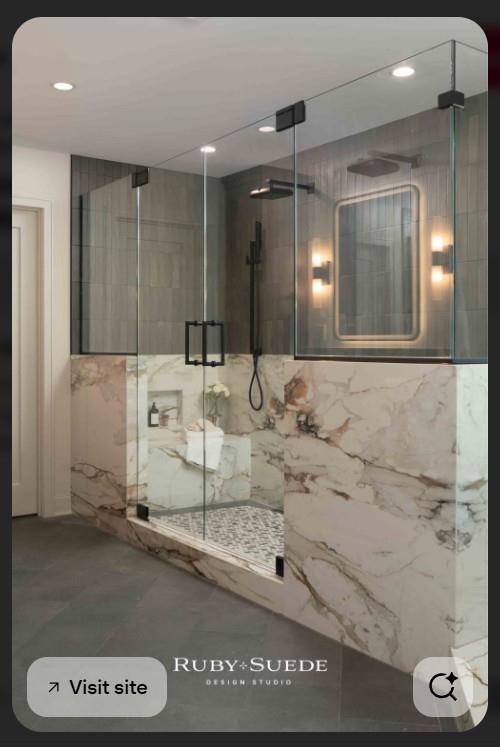 Modern walk-in shower with black fixtures, gray tile, and dramatic veined marble-look walls.